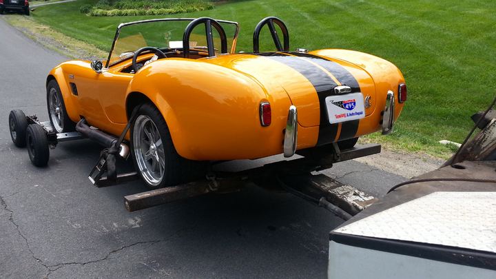 A classic roadster on a 495 Towing wheel-lift, wearing a 495 Towing & Auto Repair plate
